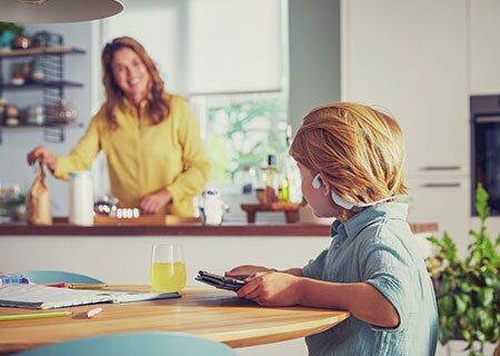 Хлопчик дивиться відео, користуючись бездротовими навушниками Philips відкритого типу